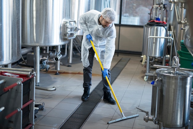 professional cleaner wearing protection uniform cleaning floor production plant